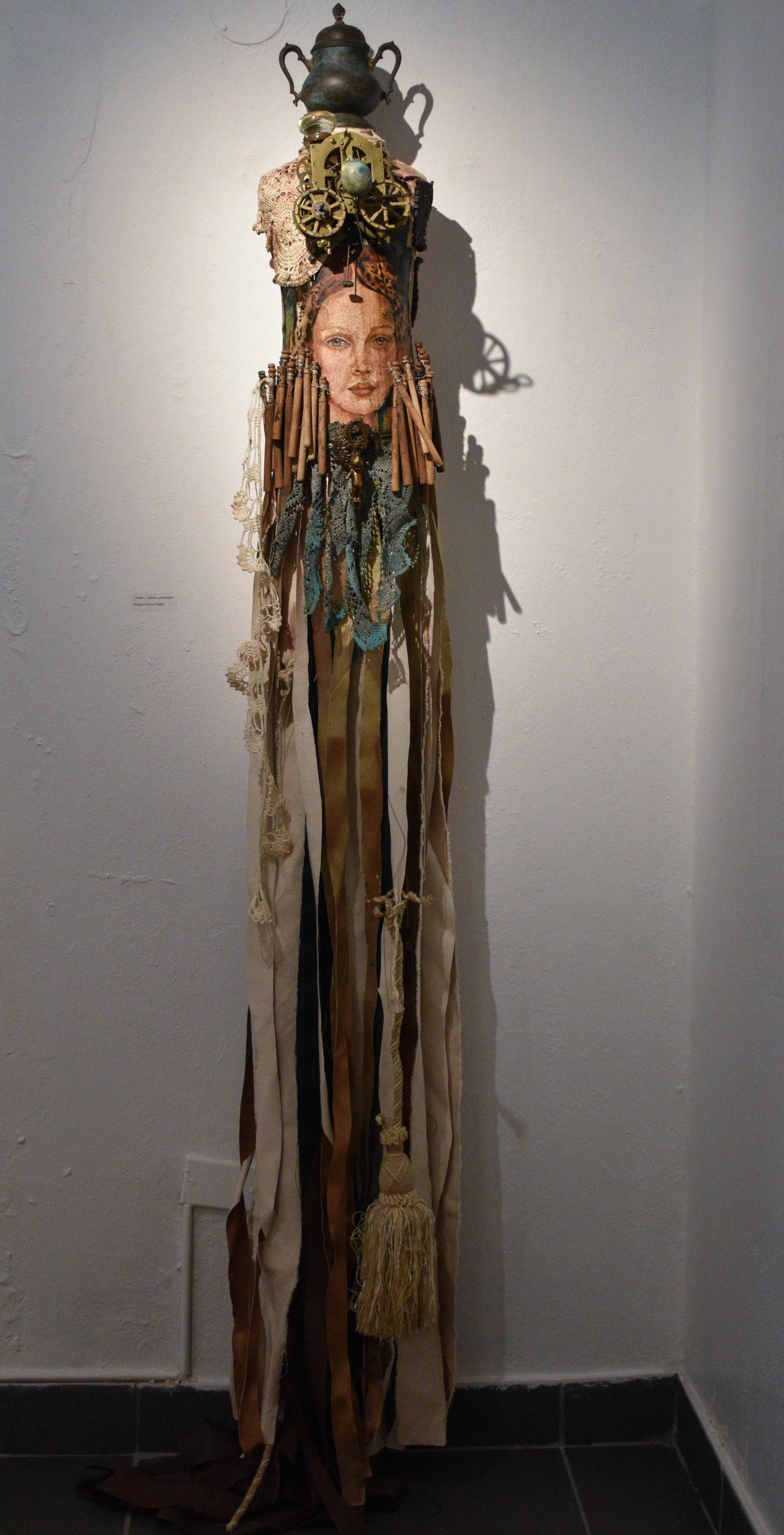 Artistic sculpture of a figure with draped fabrics and mixed media elements with a painted woman's face