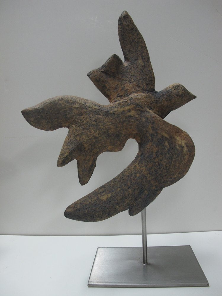 A ceramic sculpture of a bird mounted on a stainless steel base.