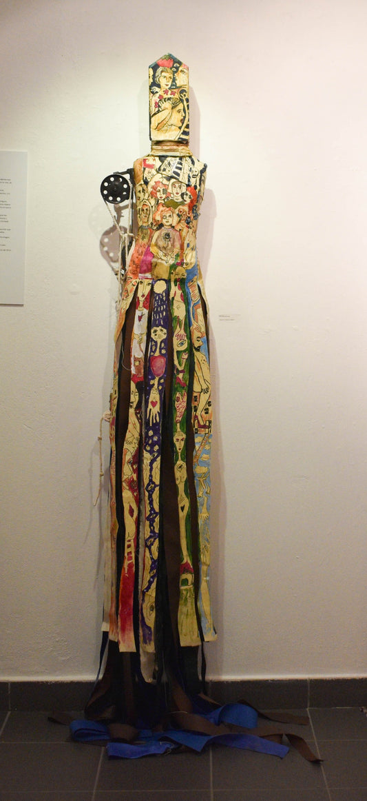 Colorful dress sculpture with mixed  patterns and decorative elements on a mannequin.