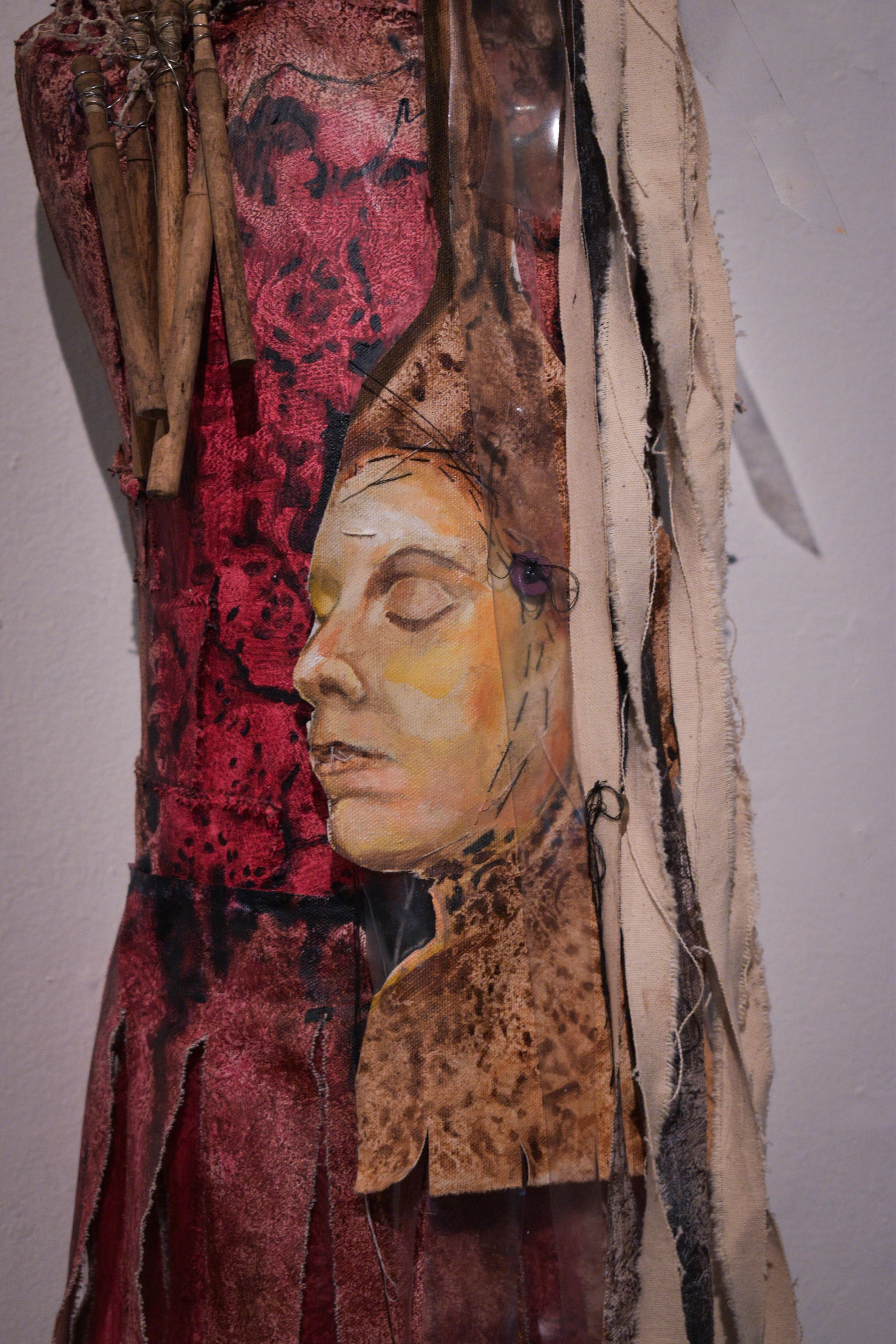 Textile art piece with a face design on painted mannequin