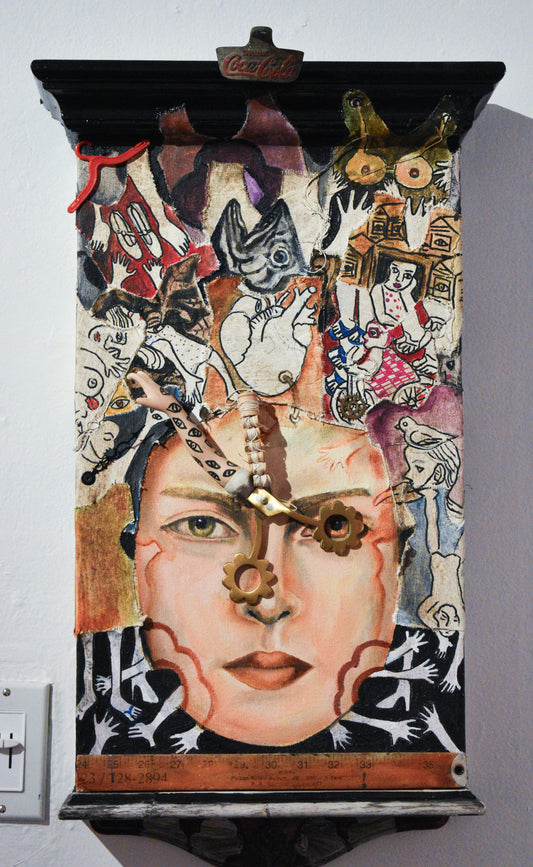 Collage art piece with a face and various elements on a wooden board.